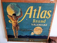 Wooden fruit crate end with Atlas Brand Valencias advertising, showing a muscular man holding a globe, with vibrant yellow text on blue background