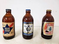 Three full stubby brown glass beer bottles from the 1970s with vintage labels: Blue Star, Labatt's Royal Blue 1924-1984, and Molson Export.