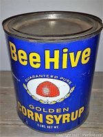 Front view of a blue metal Bee Hive Golden Corn Syrup tin with yellow text and red beehive logo