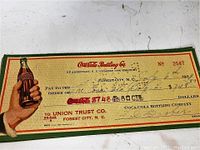 Vintage Coca-Cola Bottling Co cheque from 1939 with detailed writing and large Coca-Cola bottle image.
