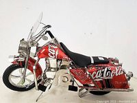 Side view of the Coca-Cola motorcycle model showing detailed construction from aluminum cans, including windshield, seat, wheels, and can text graphics.