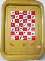 Front of the rectangular metal tray featuring Coca-Cola logos, Montreal 1976 Olympic Games pictograms, and emblems in red and white on a yellow-beige background.