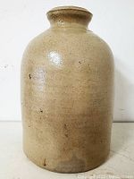 Front view of beige glazed stoneware crock with narrow neck and rounded body