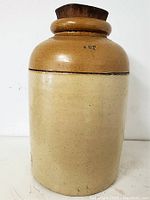 Front view of a two-tone glazed stoneware crock with a wooden top lid.