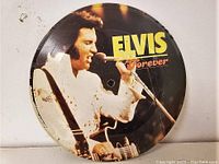 Front side of Elvis Presley 7 inch picture disc, showing Elvis in white outfit performing with guitar and microphone and 'ELVIS Forever' title.