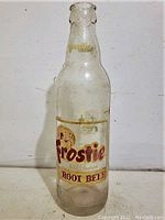 Front view of vintage Frostie Root Beer glass bottle showing label and embossed neck.