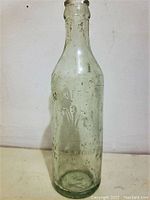 Full front view of the embossed clear bottle showing lettering and decoration