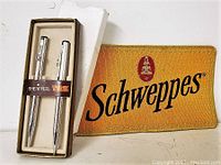 Sheaffer pen and pencil set in original box next to Schweppes branded cloth badge.