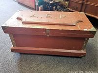 Side angle photo showing the full length and shape of the wooden chest with metal corners and latch.