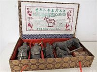 Top view of open fabric-covered box showing five terracotta warrior figurines and informational Chinese text insert.