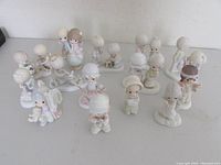 Group of 14 Precious Moments figurines arranged on table, showing overall lot contents and condition.