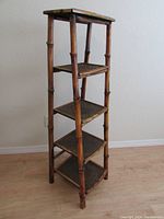 Side view of the antique bamboo folding shelf showing four woven shelves and folding mechanism.
