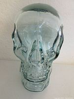 Front view of clear recycled glass skull mannequin, showing detailed facial bone features with light aqua tint