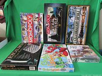 Overview of all 6 board games in their boxes including Monopoly Disney Edition, Monopoly Star Wars Classic Trilogy Edition, Celebration Opoly, MU sealed, Chutes & Ladders Superhero Squad, and Excalibur King Master Electronic Chess & Checkers.