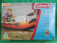 Photo of Coleman branded box packaging of a 2-person inflatable touring kayak, showing an image of two people in the kayak on water and brand labeling.