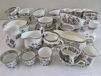 Full lot of mixed Indian Tree pottery items including cups, saucers, plates, creamers, and bowls arranged on a surface to show quantity and variety.