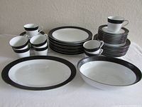Full lot group showing the 42 pieces evenly arranged including stacked dinner plates, salad plates, bread plates, cups and saucers, oval vegetable bowl and serving platter.