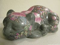 Side angle showing the green-gray marble effect and pink floral decorations on the sleeping cat figurine.