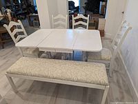 Dining room set showing table with all sides extended and 4 chairs around it plus the bench in front