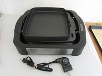 Photo showing the flat griddle plate resting on top of the base unit with temperature control cord and knob attached.