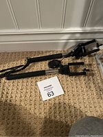 Two phone selfie sticks on carpet, one has attached Bluetooth remote shutter button on handle.