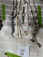 Overall photo showing the multiple necklaces and the wristwatch laid out on fabric surface.