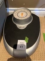 Top view of the Health o meter bathroom scale showing the black and silver body with round dial display facing front. The scale has a MaxSold auction tag labeled 41 on the foot platform.