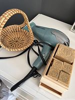 Photo showing Conair hairdryer, woven wicker basket, and wooden box with hand soaps on white surface.