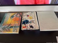 Two 11x14 canvases and one white plastic paint palette showing paint stains