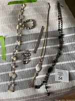 Full lot of assorted costume jewelry displayed on a striped cloth, including necklaces, bracelets and earrings.