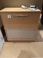 Front view of IKEA Effektiv file drawer cabinet with roll door bottom, showing light wood finish and metal handles.