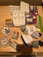 Photo of assorted international travel plug converters and multi-socket power outlets arranged on wooden surface.