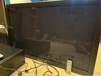 Panasonic 50 inch plasma TV with remote and cables visible on the surface below TV.