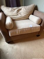 Front view of beige microfiber chair and a half with large back cushion and two bolster pillows on beige carpet.