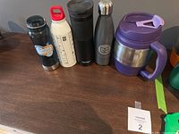 Full view of all five water and coffee bottles showing various sizes and colors including purple Bubba mug and Contigo travel mug