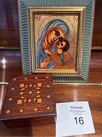 The painted wooden icon and the closed wooden box with inlaid pattern shown together on a wooden surface.