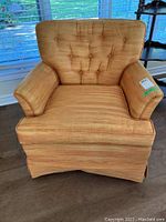 Front view of an upholstered armchair with tufted back and warm orange striped fabric.