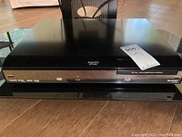 Front and top view of Sharp AQUOS Blu-ray player with visible product labels and brand markings.