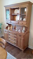 Front right angle view of the wood china cabinet with hutch and buffet, showing drawers, cabinets, metal handles, and shelving with some display items (not included).