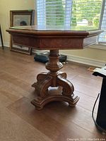 Full view of the wooden octagon-shaped end table showing the tabletop, carved edge, and pedestal base.