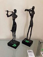 Two metal musician figures on black square bases, one playing flute and the other violin.
