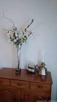 Photo showing all three items on wooden dresser: antique iron, oil lamp with chimney, tall glass vase with faux white flowers and green leaves