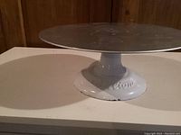 Full image of the Wilton cake decorating turning stand showing cast iron base and aluminum turning top.