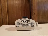 Front view of the antique Doultons pottery foot warmer with text and decoration visible.