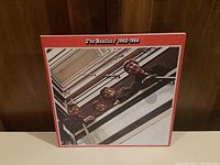 Front cover photo of The Beatles 1962-1966 vinyl album showing the band members looking down from a balcony with red border and white text.