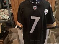Front view of black Pittsburgh Steelers jersey with number 7, NFL logo at neckline, and Steelers team patch on upper right chest.