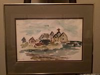 Full frontal photo of the framed painting showing a coastal village in watercolor with muted colors and a mat border.