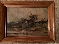 Front view of the framed oil painting showing the cabin by the stream with trees and fence