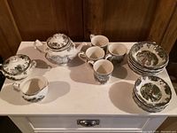 Full set arranged showing teapot, creamer, sugar bowl, coffee mugs, plates and bowls.
