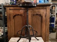 Full view of vintage industrial adjustable stool showing dark metal frame and round wooden seat.